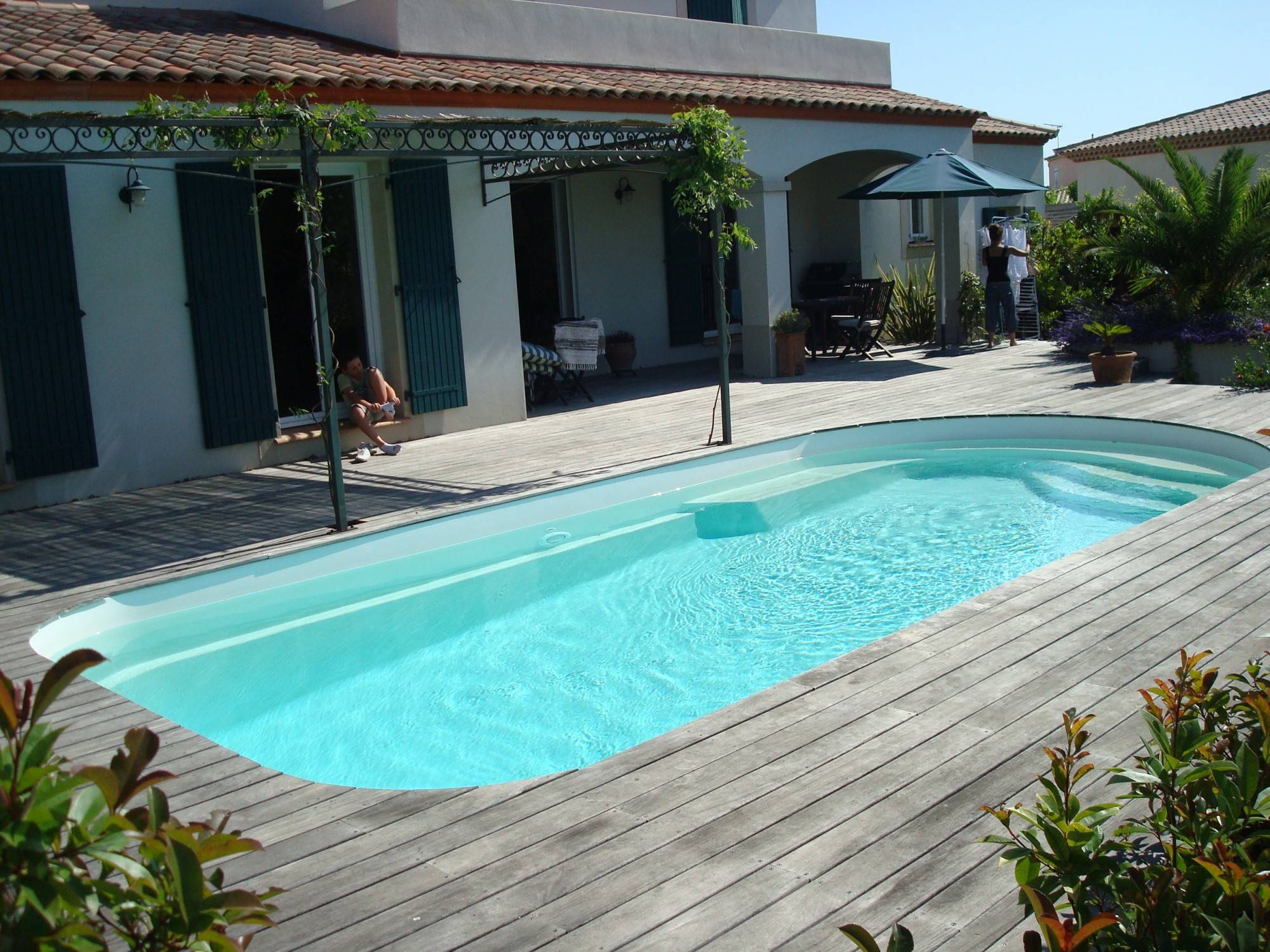 Piscine coque blanche avec terrasse bois formes arrondies et banquette- Ferré Piscines sur Allauch