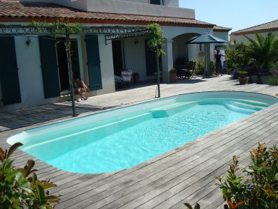 Piscine coque blanche avec terrasse bois formes arrondies et banquette- Ferré Piscines sur Allauch